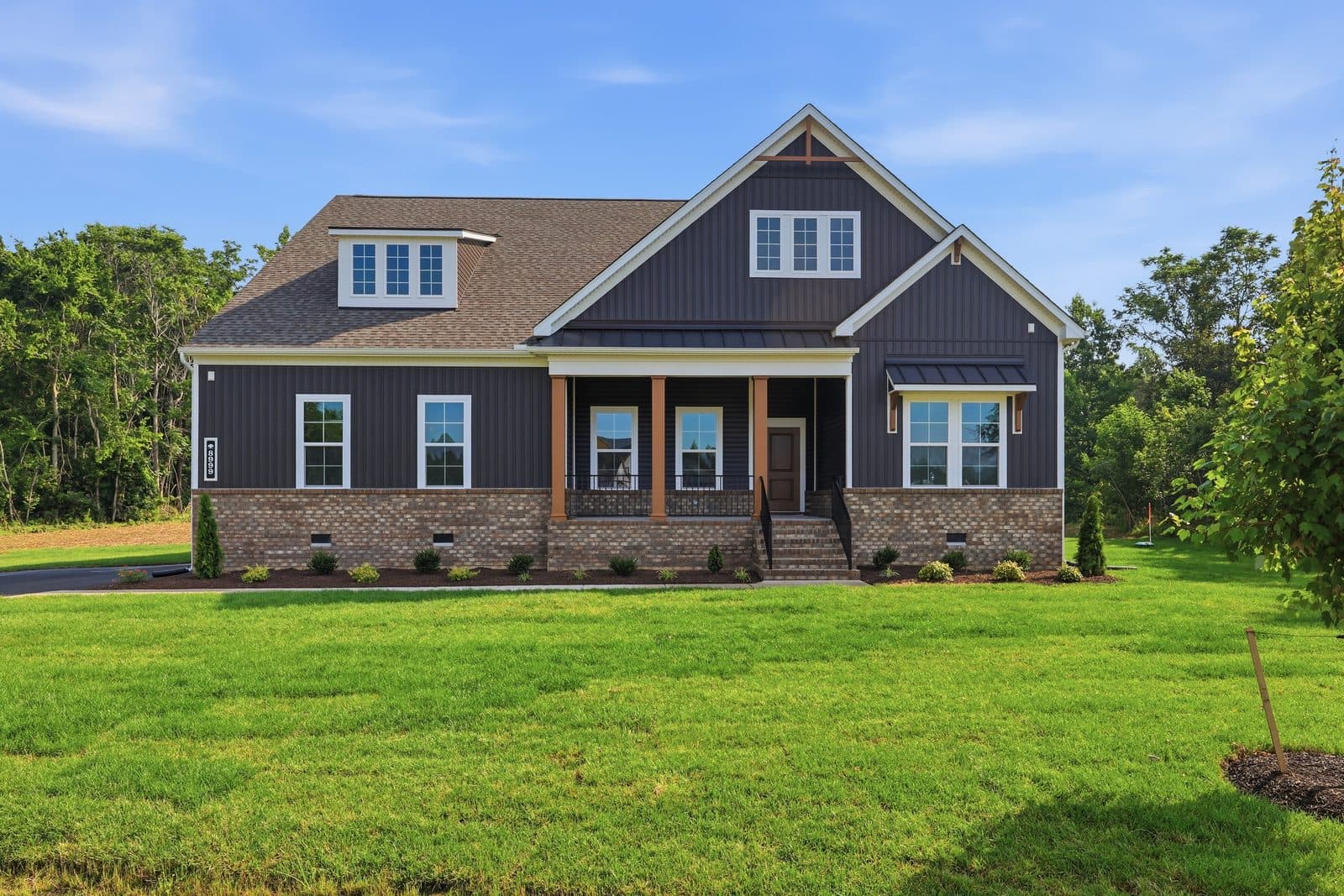 Dark custom craftsman home with stone base and covered porch