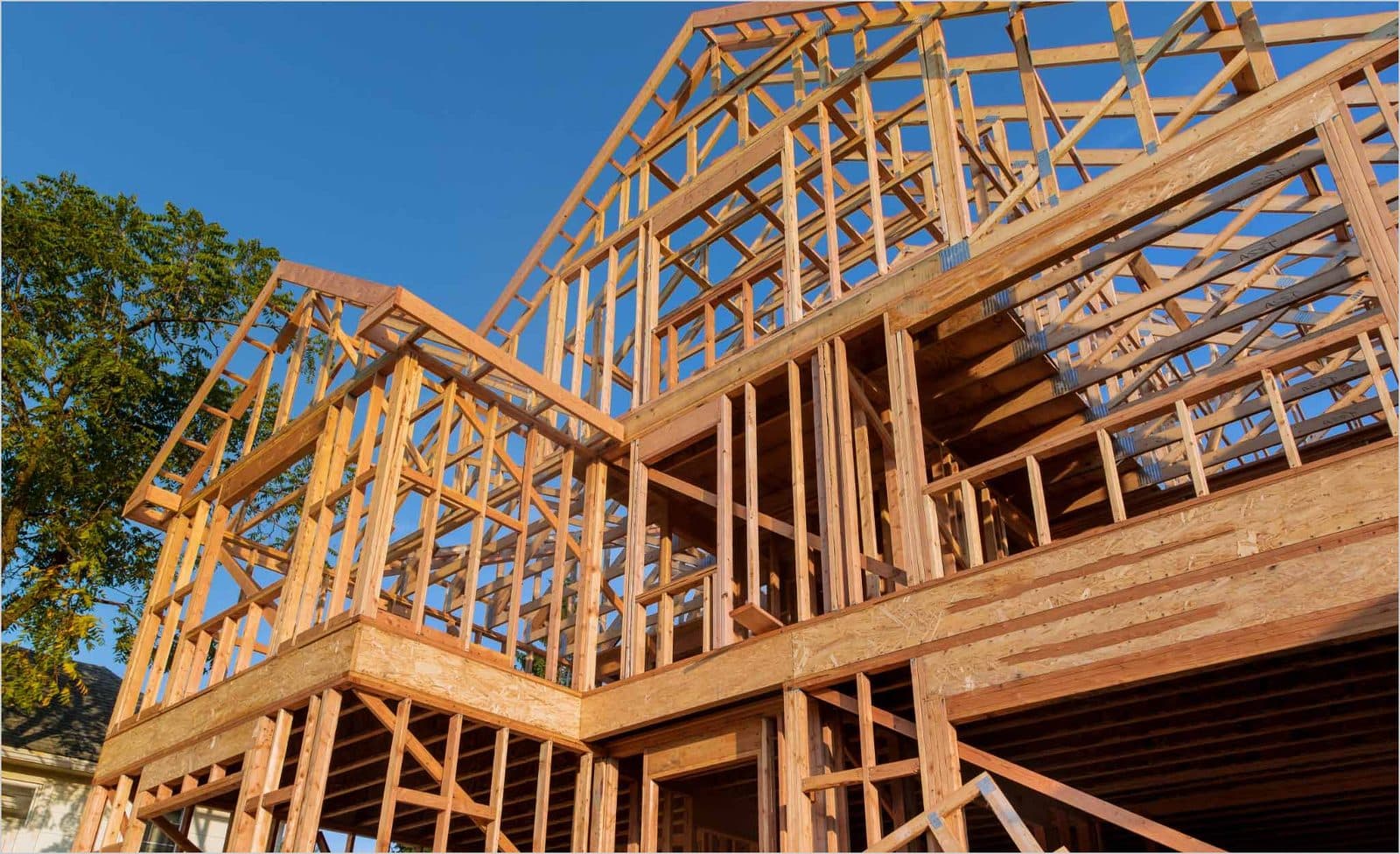 Timber frame of a new home under construction against a blue sky