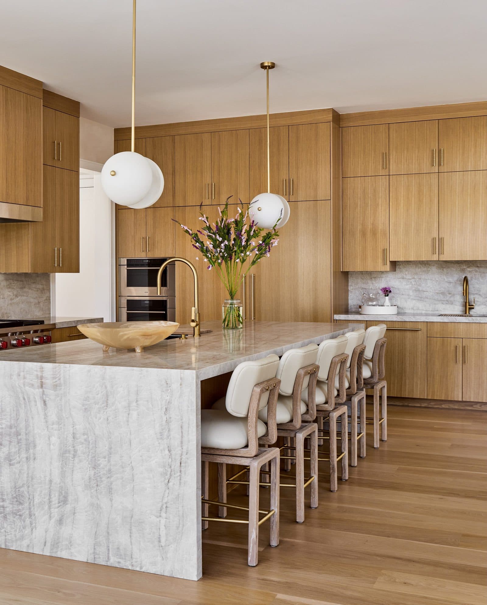 Warm oak kitchen with a marble island and brass pendants