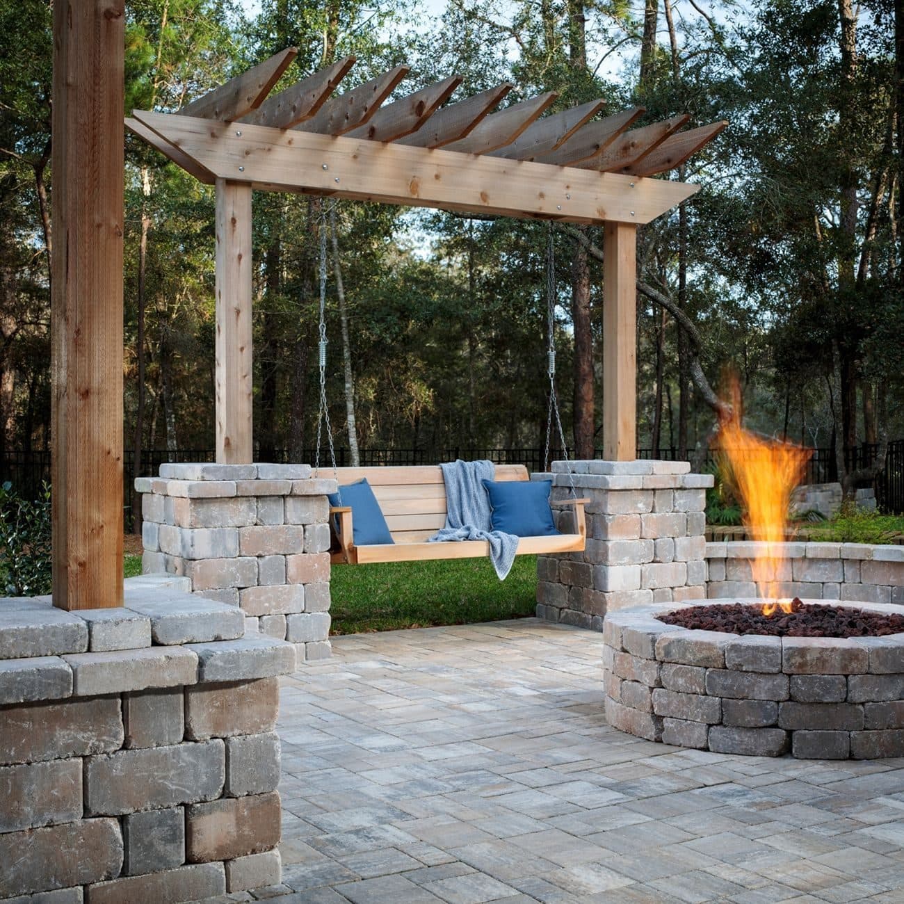 Paver patio with a pergola swing and a stone fire pit