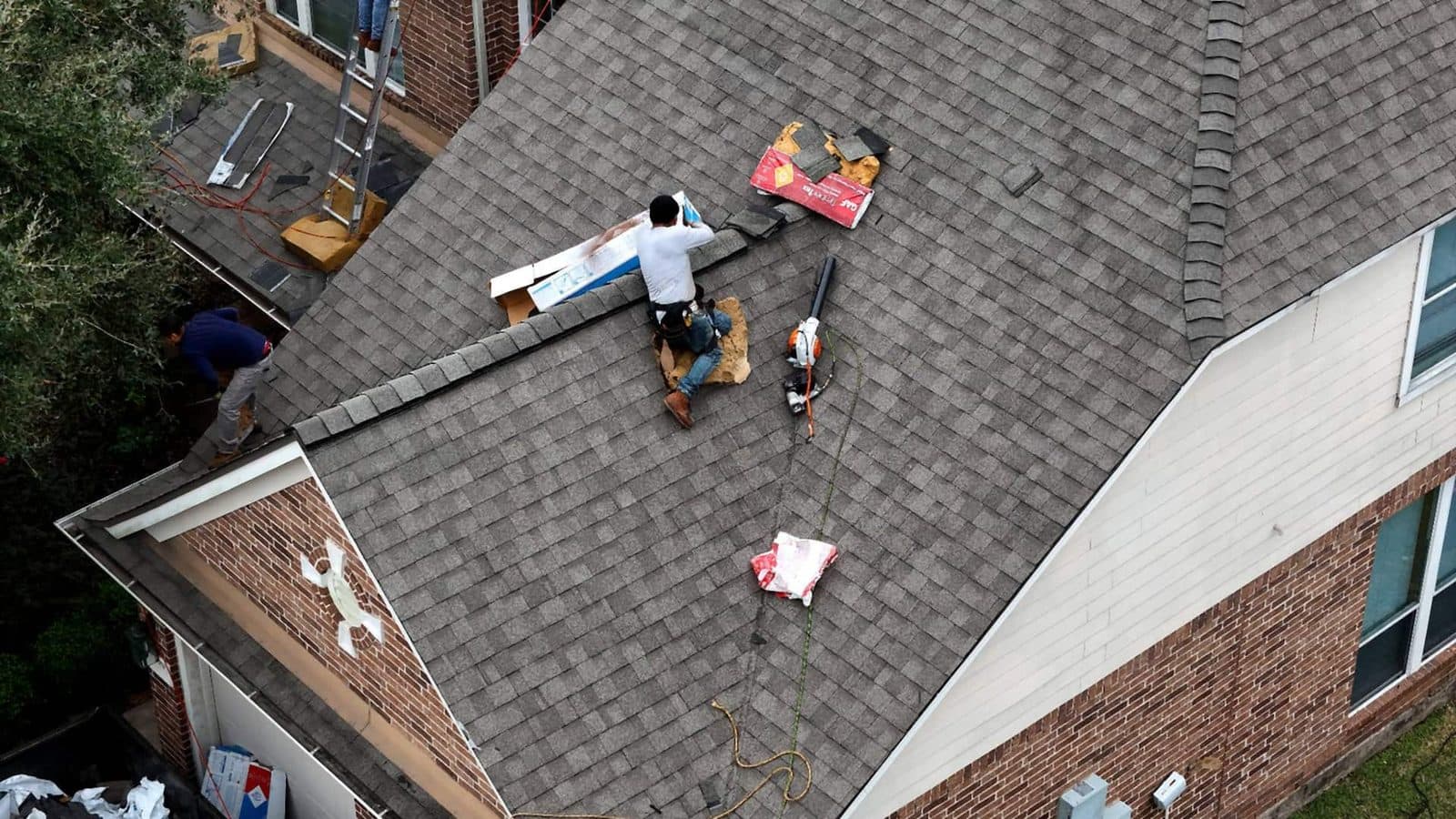 Aerial view of roofers finishing a shingle roof on a large home