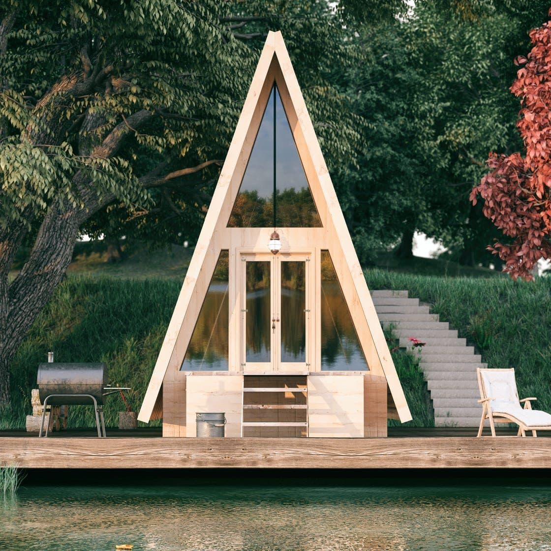 A-frame tiny cabin by the water surrounded by trees